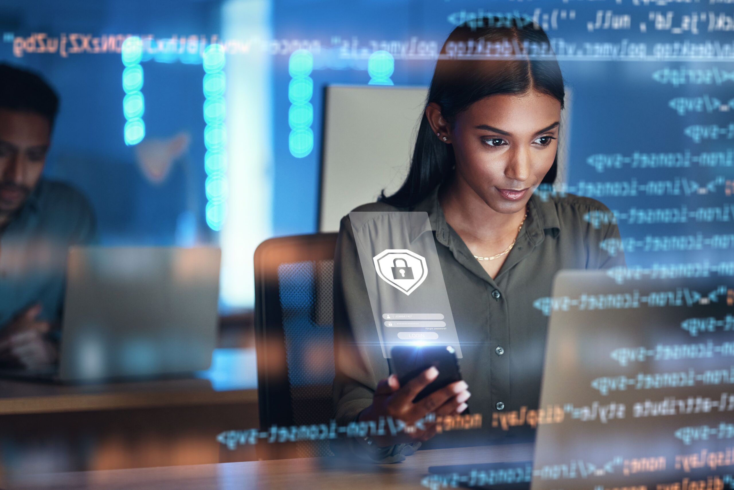 Woman looking into her computer while holding a phone to conduct data security for a banking application.